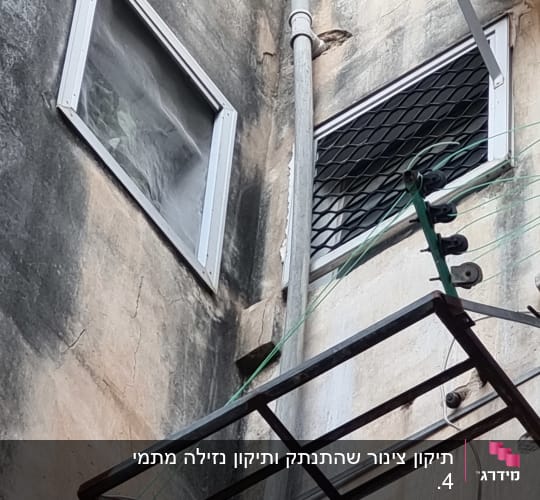 צינור מתכת על קיר חיצוני עם חלונות וסורגים